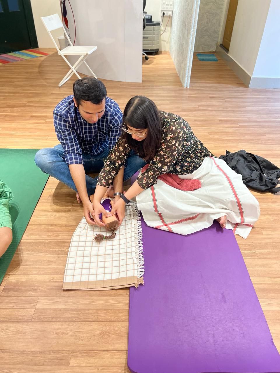 Image of parents actively participating in a hands-on infant care session at Aura Birthing Partner.